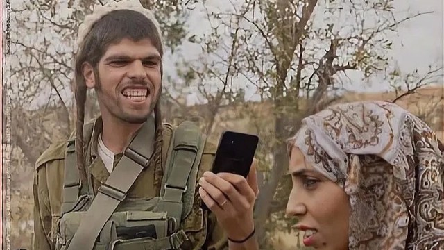 Fotografija prikazuje naoružanog izraelskog doseljenika kako snima Palestinku u teškoj situaciji.